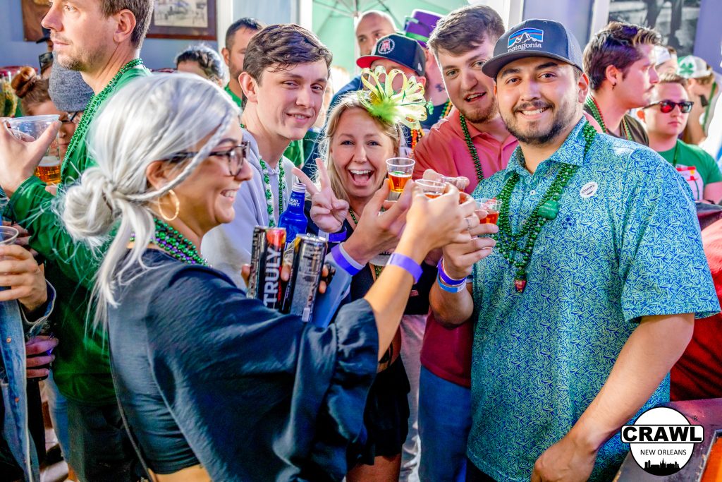 A group of friends smiling and posing for a photo at a New Orleans bar during a VIP crawl in the French Quarter